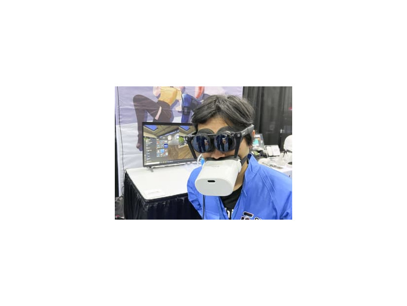 仮想現実（VR）対応端末を装着して来場者に説明するパナソニックの子会社シフトールの岩佐琢磨CEO＝3日、米ラスベガス（共同）