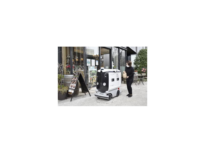 弁当を配達ロボットに入れる店員＝25日午前、東京・大手町