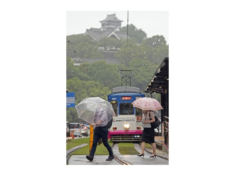傘を差して熊本市内を歩く人たち。上は熊本城＝5日午前8時11分