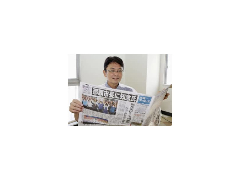 那覇市長選から一夜明け、初当選を報じる新聞を手にする知念覚氏＝24日午前、那覇市