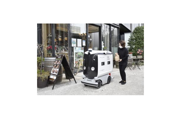 弁当を配達ロボットに入れる店員＝25日午前、東京・大手町