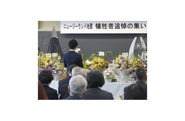 富山外国語専門学校で開かれた追悼の集いであいさつする在校生代表（奥）＝22日午前、富山市