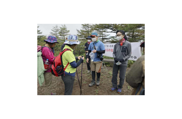 浅間山の黒斑コース登山口で、登山者（左側）に安全な登山を呼びかける「山びこの会」のメンバーら＝4日午前