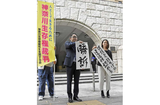 生活保護費減額処分の取り消しなどを求めた訴訟の判決後、「勝訴」と書かれた紙を掲げる弁護士ら＝19日午前、横浜地裁前
