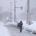 雪が降りしきる中、青森市内を歩く人＝12日午後2時22分