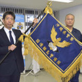 沖縄県警の「国境離島警備隊」発足式で宮沢忠孝本部長（左）から小林雅哉隊長に授与された隊旗＝1日午後、沖縄県警本部